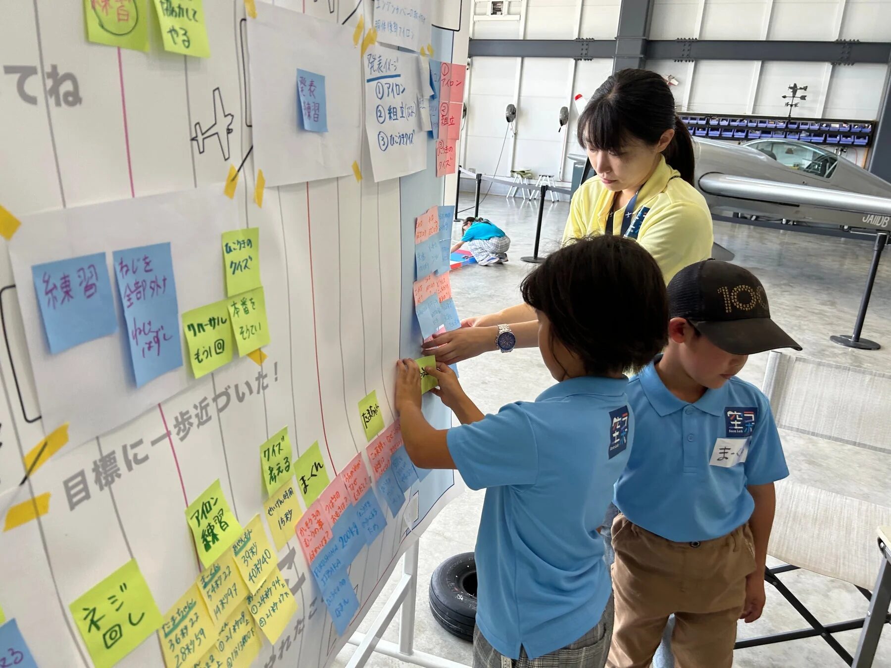 子供たちが大人と一緒にワークショップで、ポストイットを使いながら目標設定や発表練習をしている様子