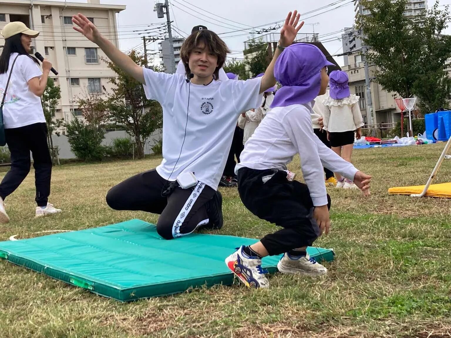 屋外で体操を指導するスタッフと子どもたち