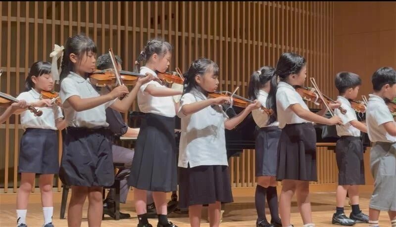 ステージ上でバイオリンを演奏する子供たち