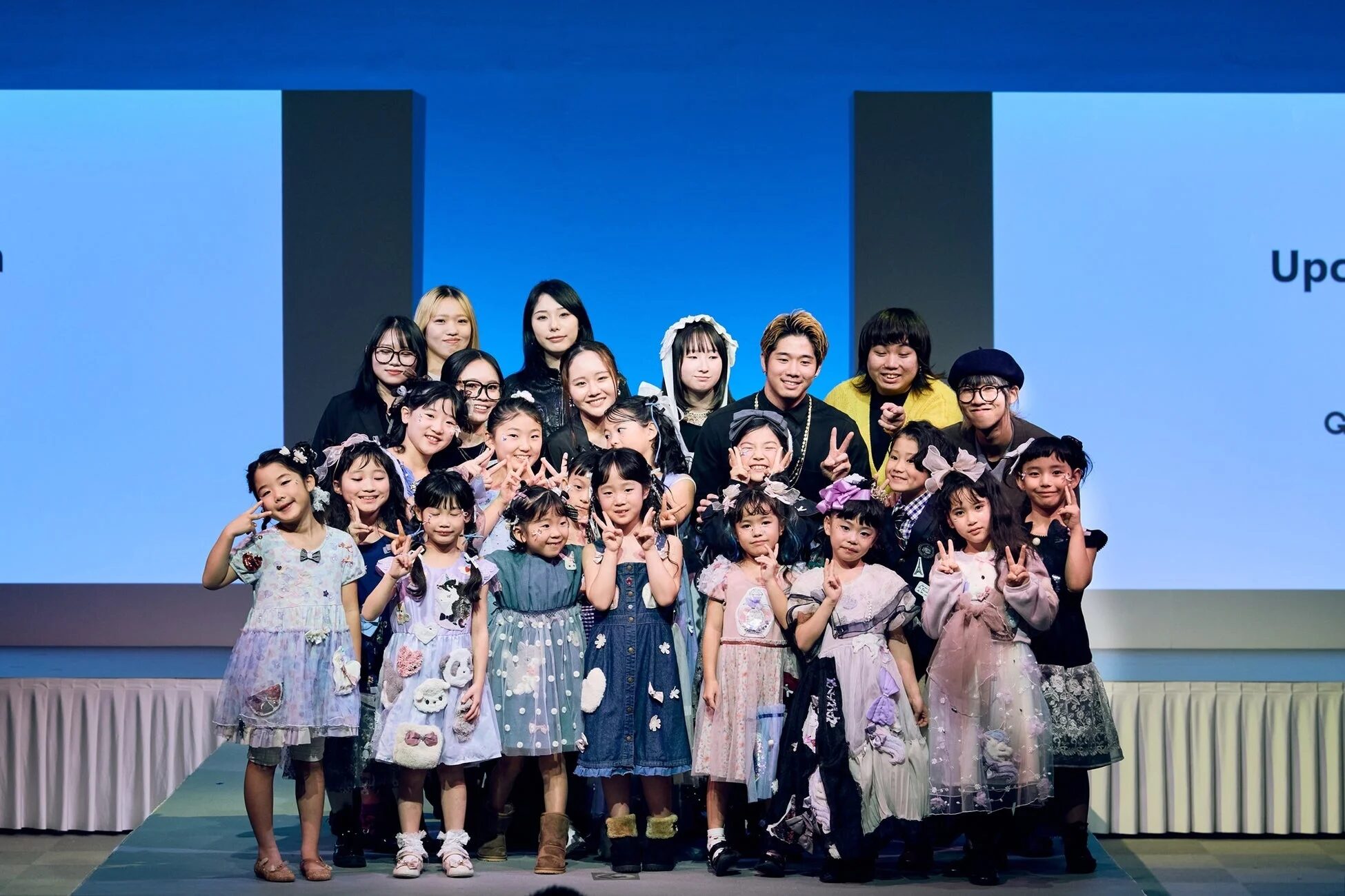 ステージ上の子供たちと大人のグループ写真