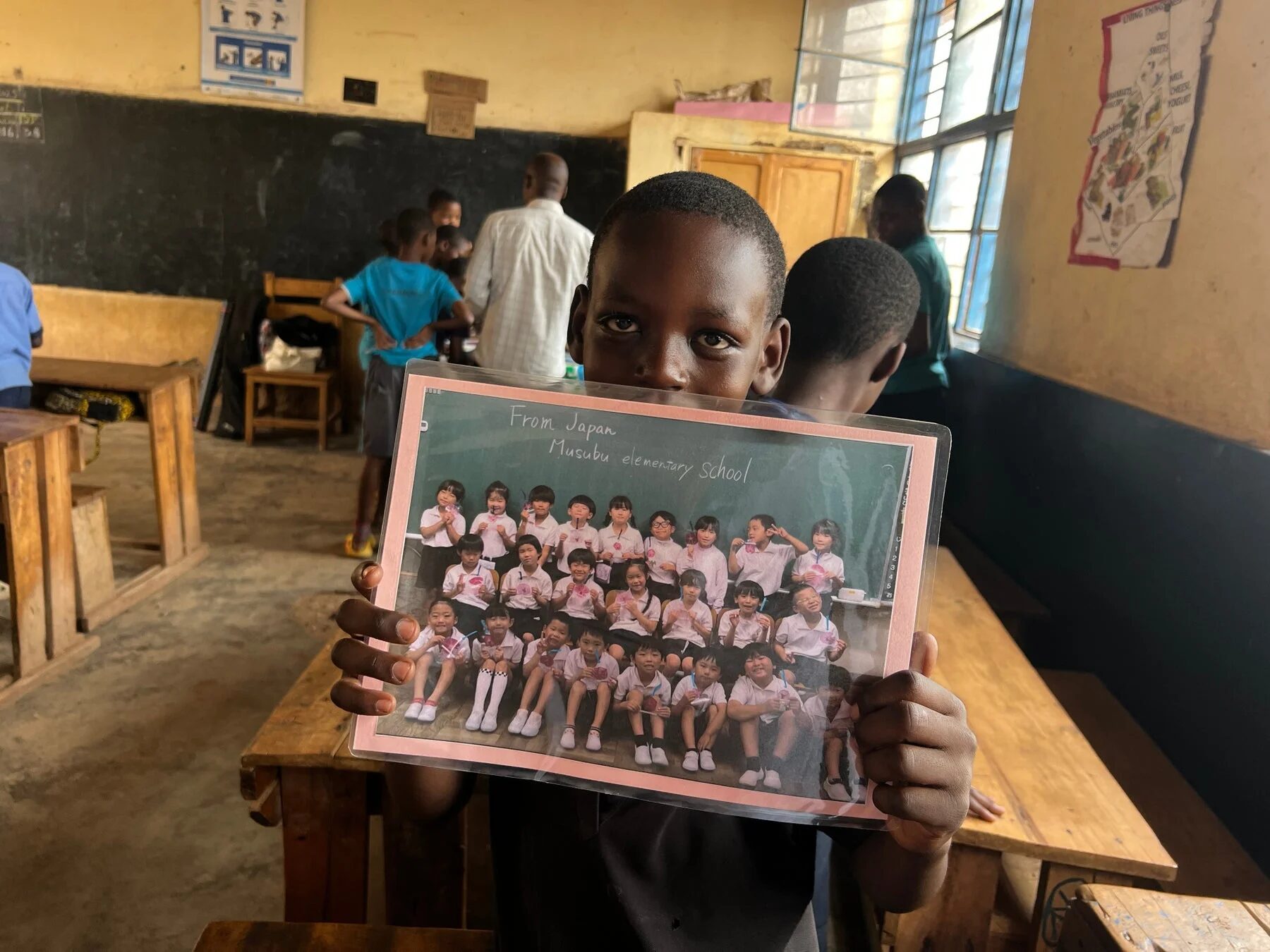 日本の小学校の写真を掲げる海外の子ども