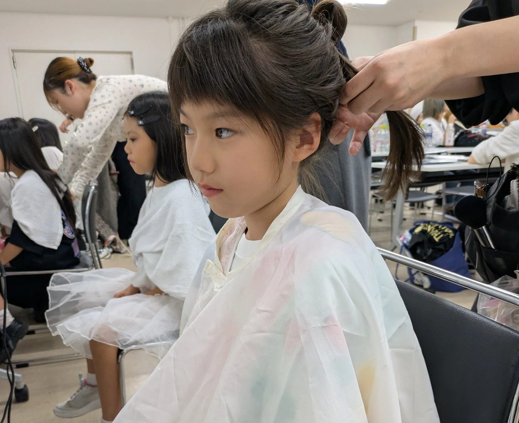 少女が大人に髪をセットしてもらっている場面