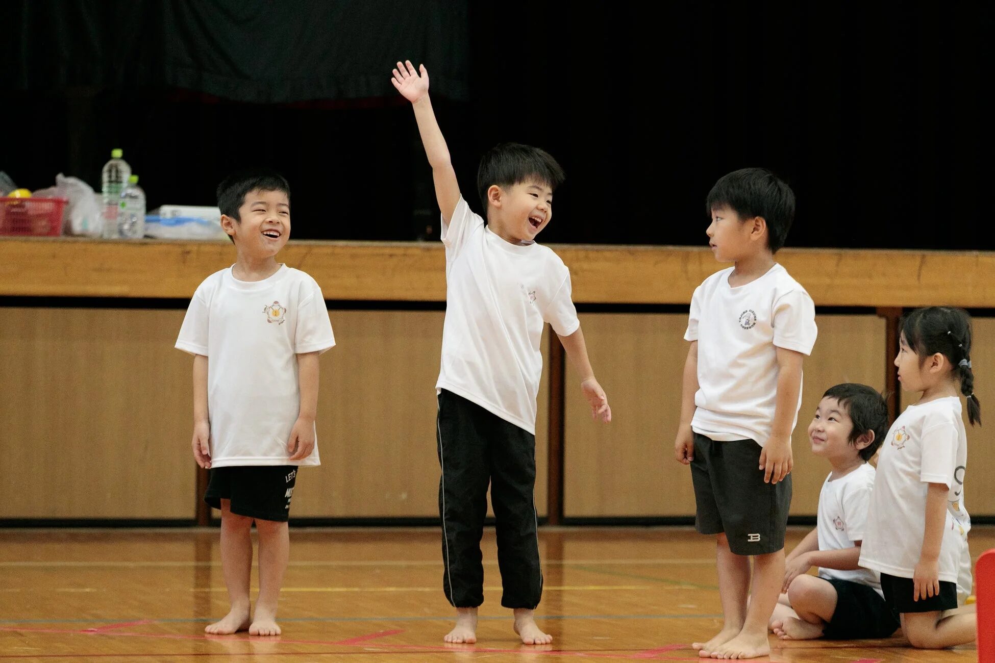 体育館で手を挙げて喜ぶ子どもたち