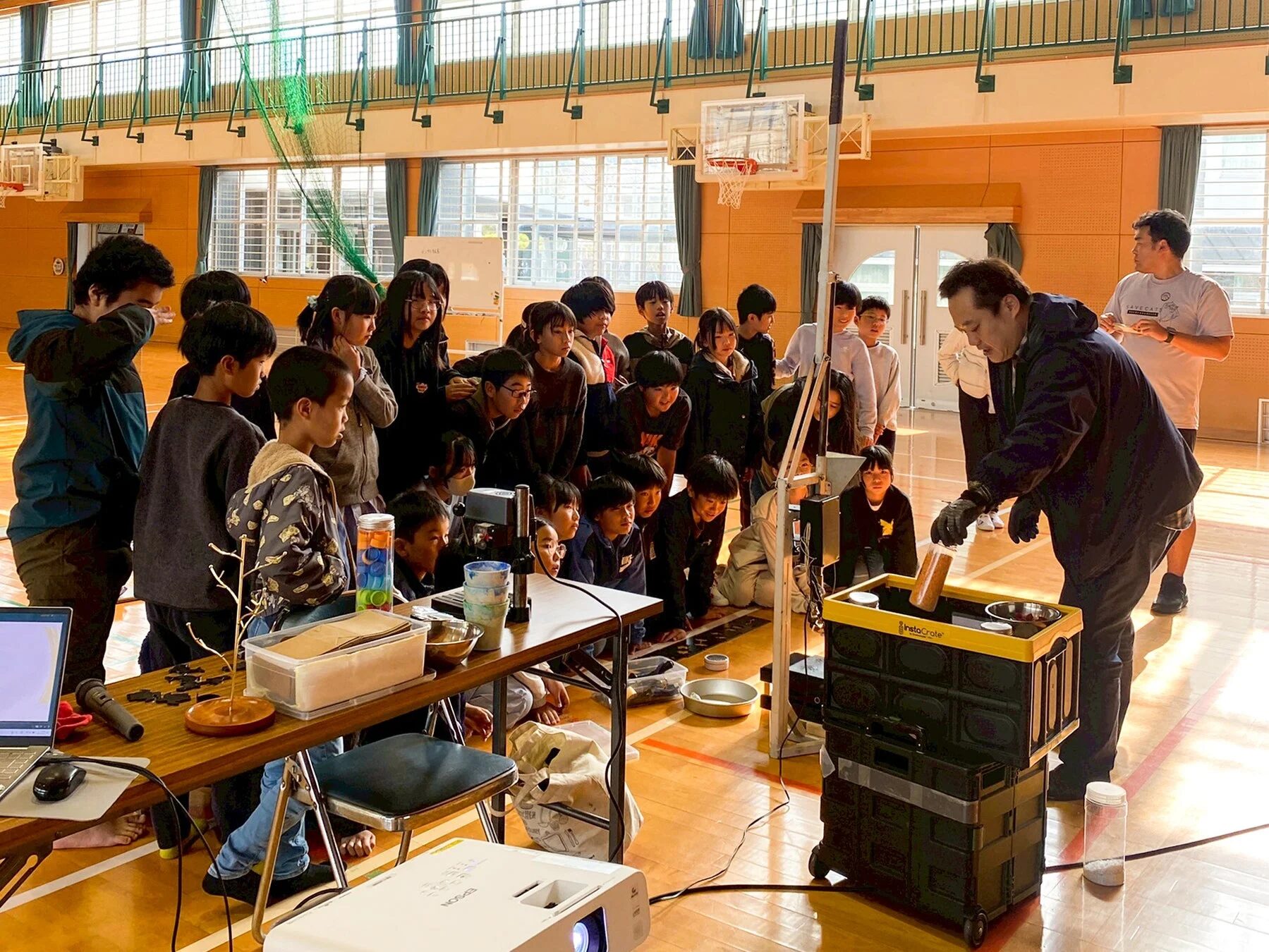 大志小学校の体育館で多くの子供たちが大人の実演を熱心に見学している様子