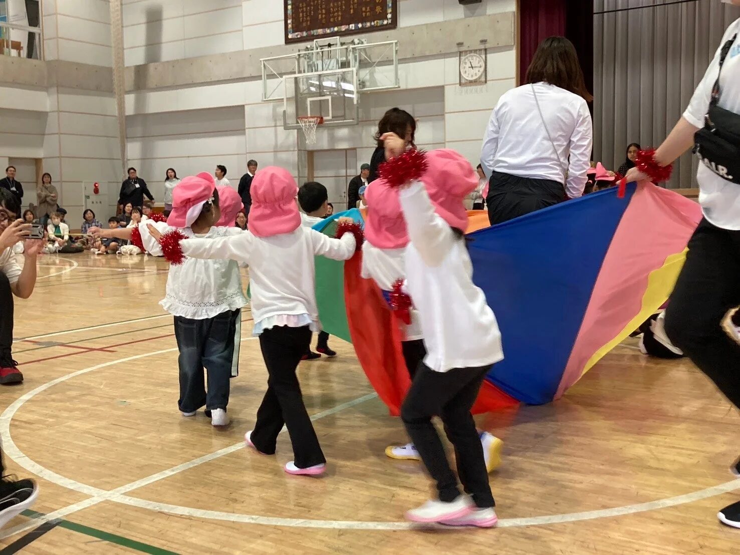 カラフルな布を持って遊戯する子どもたち