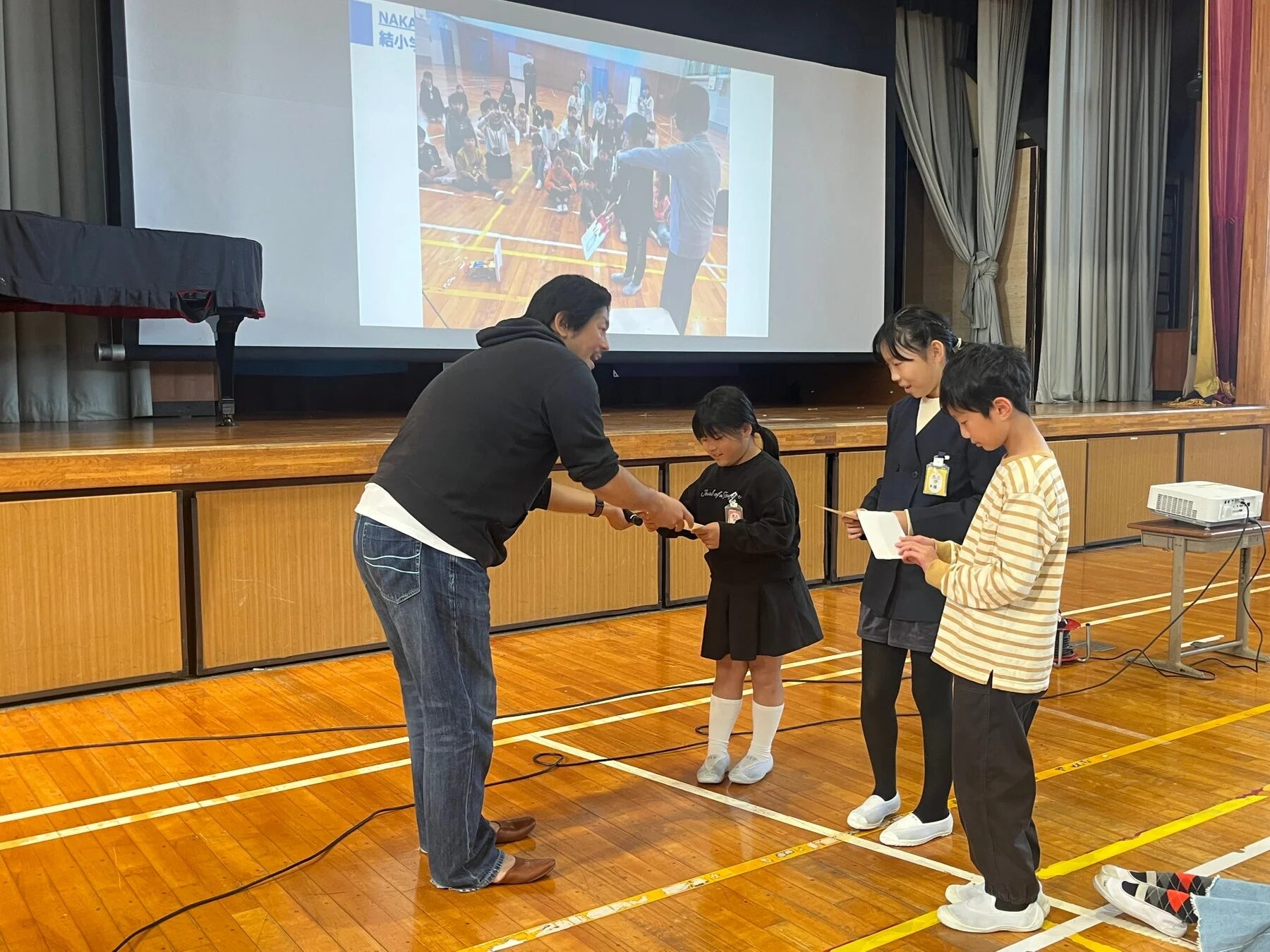 ステージで児童に何かを手渡す様子
