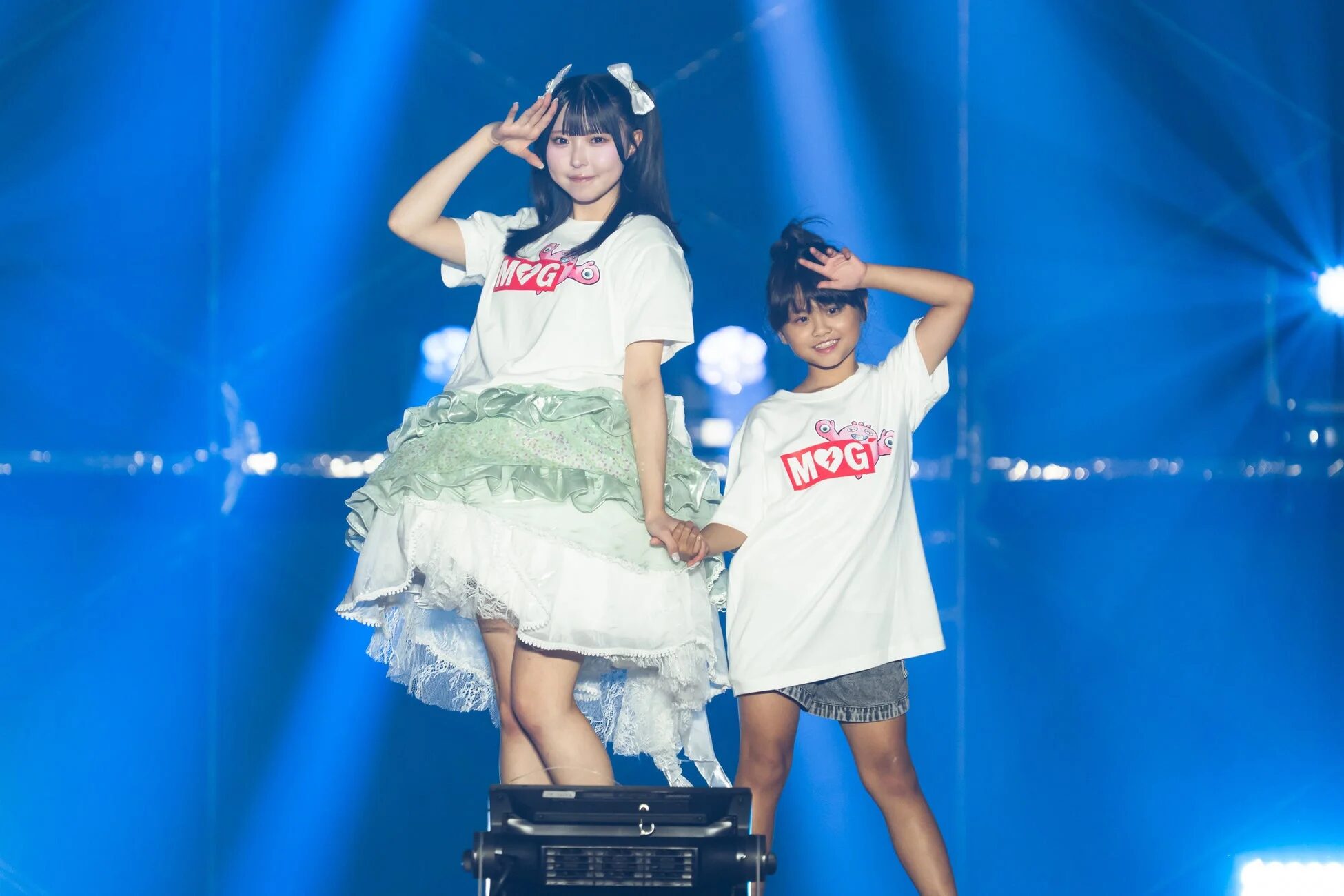 ステージで笑顔でポーズをとるアイドルと子供