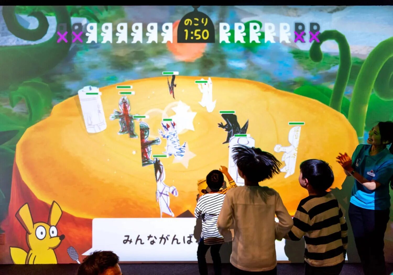 子供たちが大きな壁面に投影されたインタラクティブなゲームやアートを楽しんでいる様子