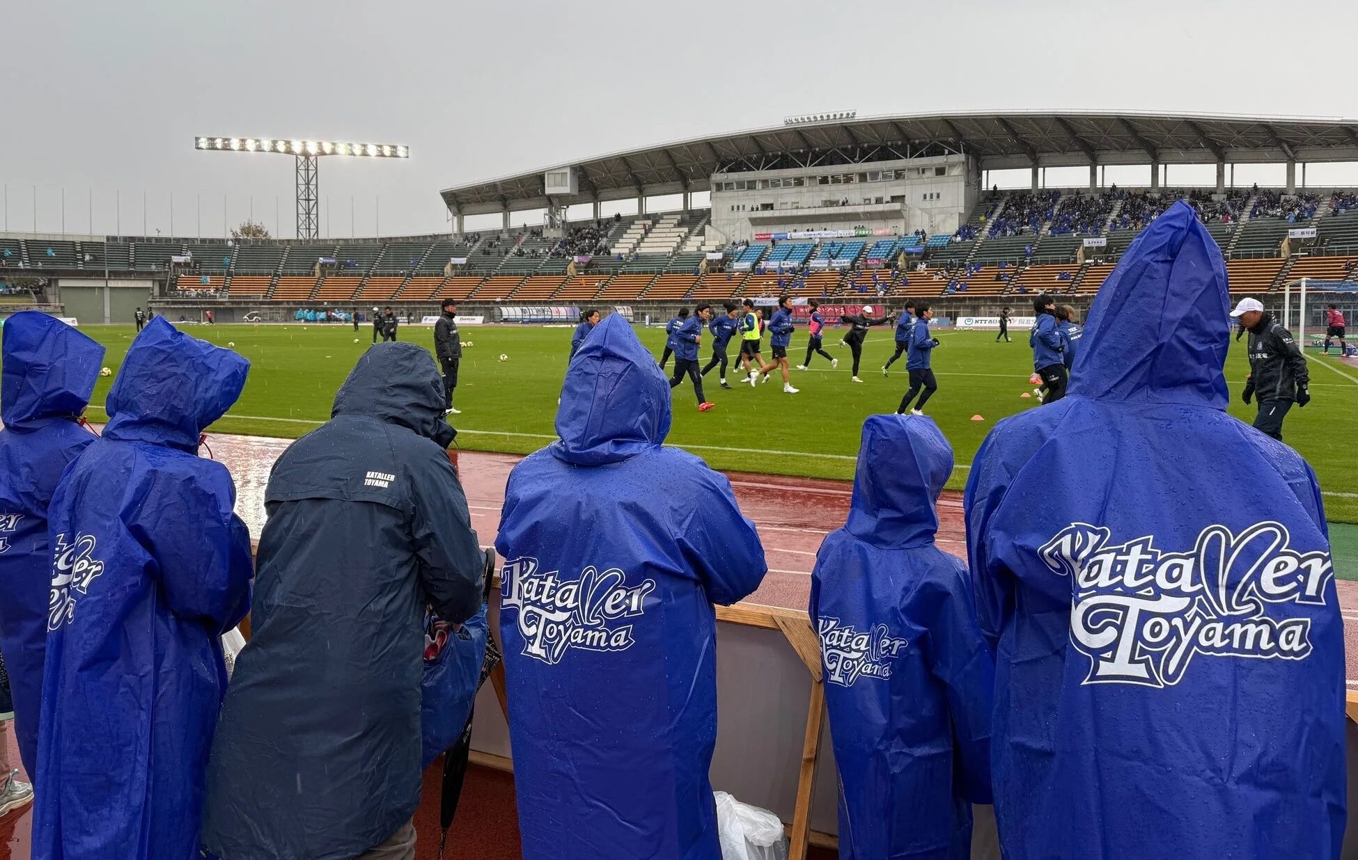 雨の中、選手の練習を見学する参加者