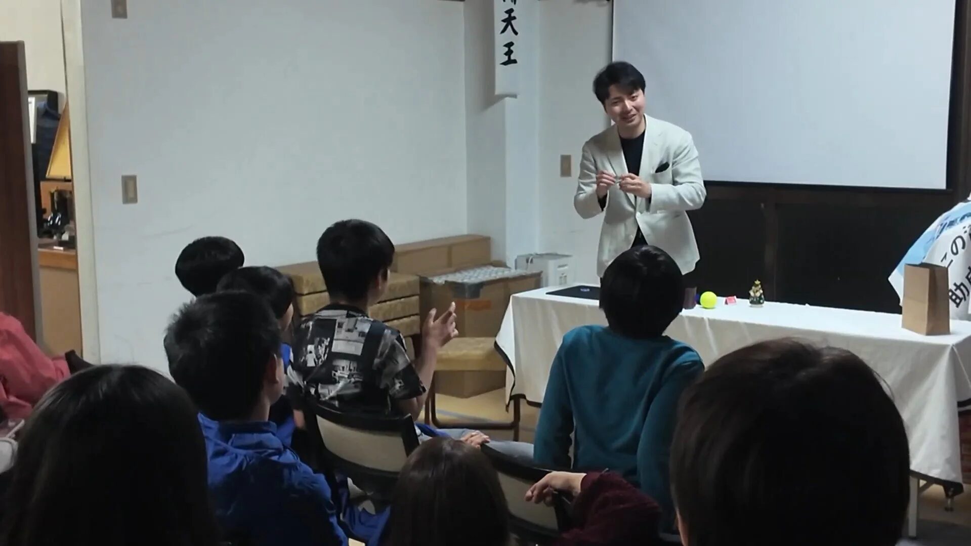 男性が子供たちを前にマジックショーのようなパフォーマンス