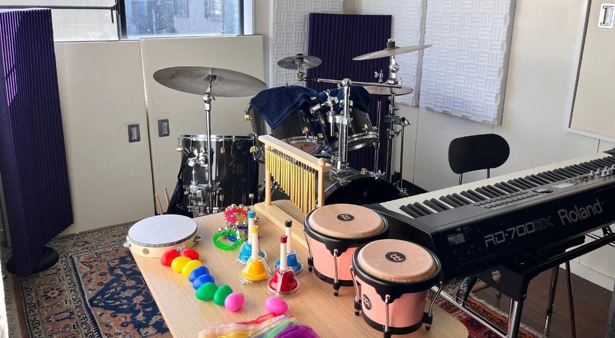 音楽室のような空間に、ドラムセット、Roland製のキーボードなどが並べられている