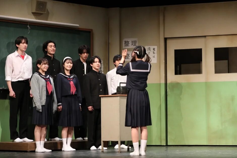教室のセットで演劇を行う学生服の生徒たち