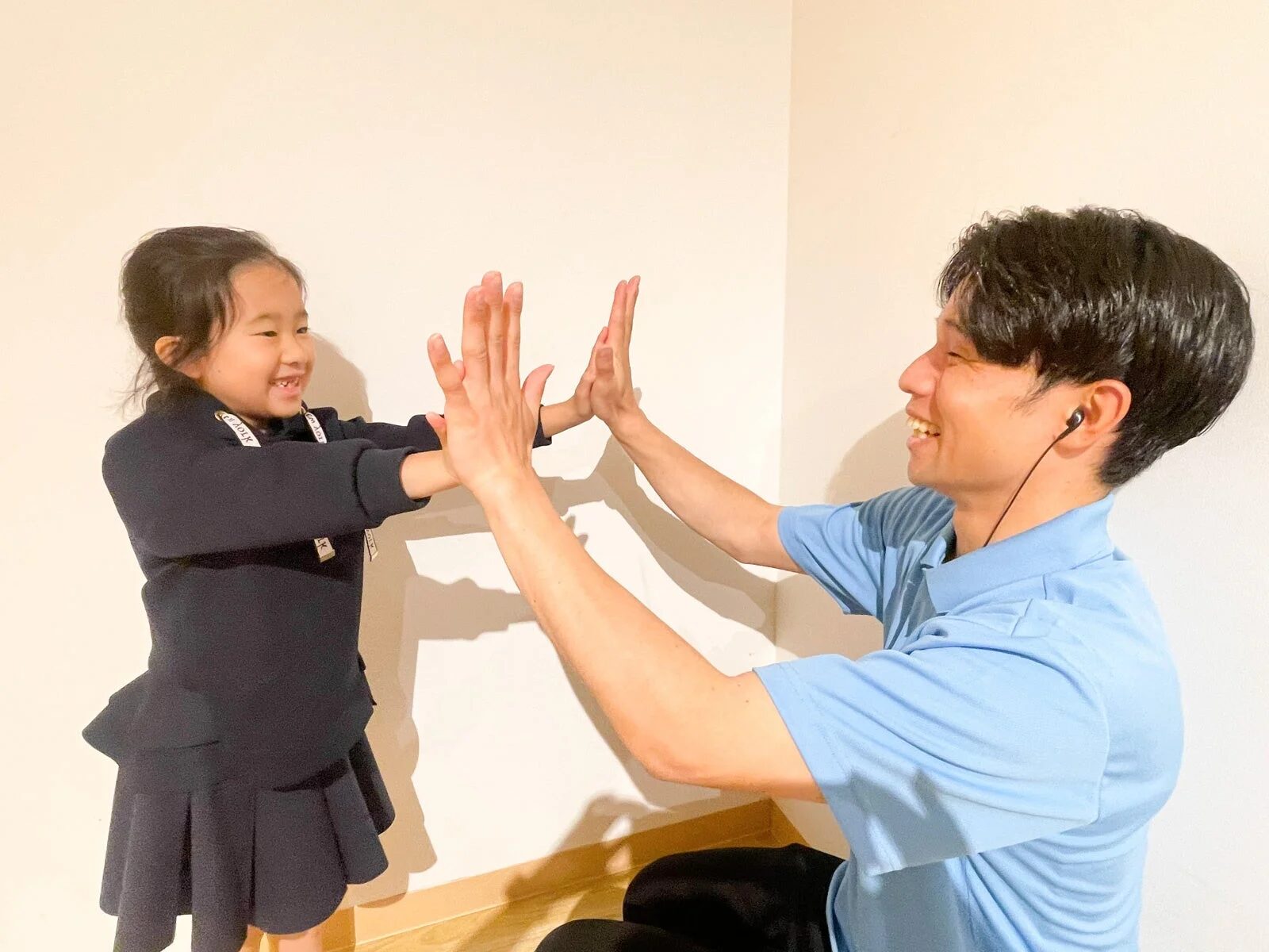 笑顔で手遊びをする大人の男性と小さな女の子