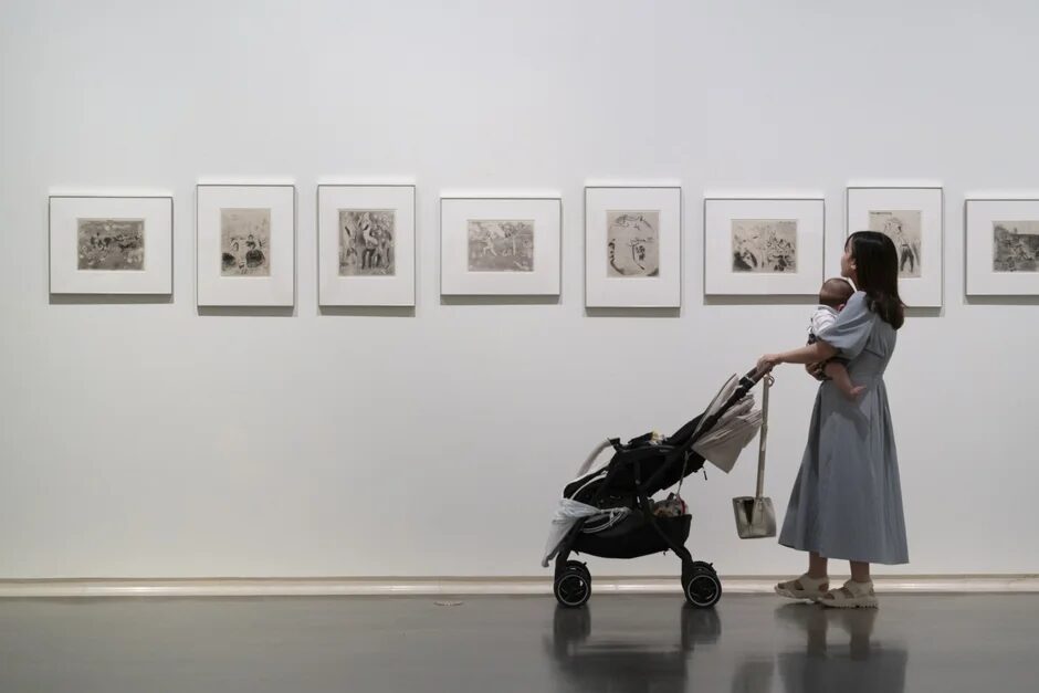 美術館で赤ちゃんを抱っこした女性が絵画を鑑賞