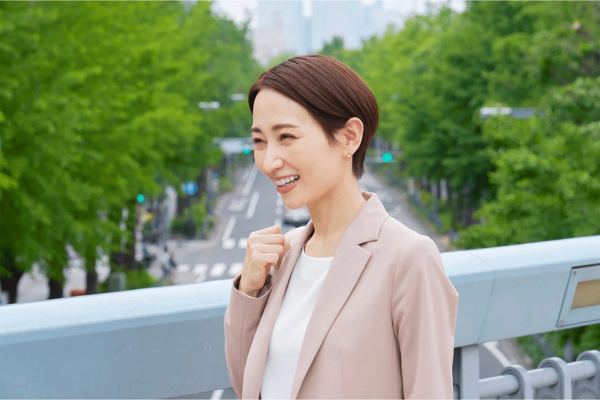 都会の背景を背に笑顔で拳を握る女性