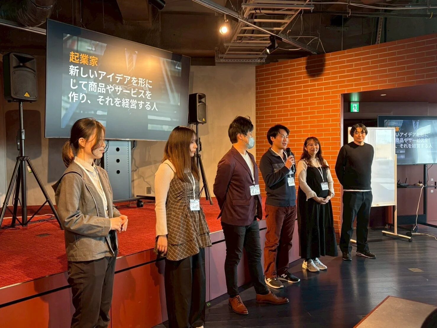 壇上で話す人とスクリーンに「起業家」の説明