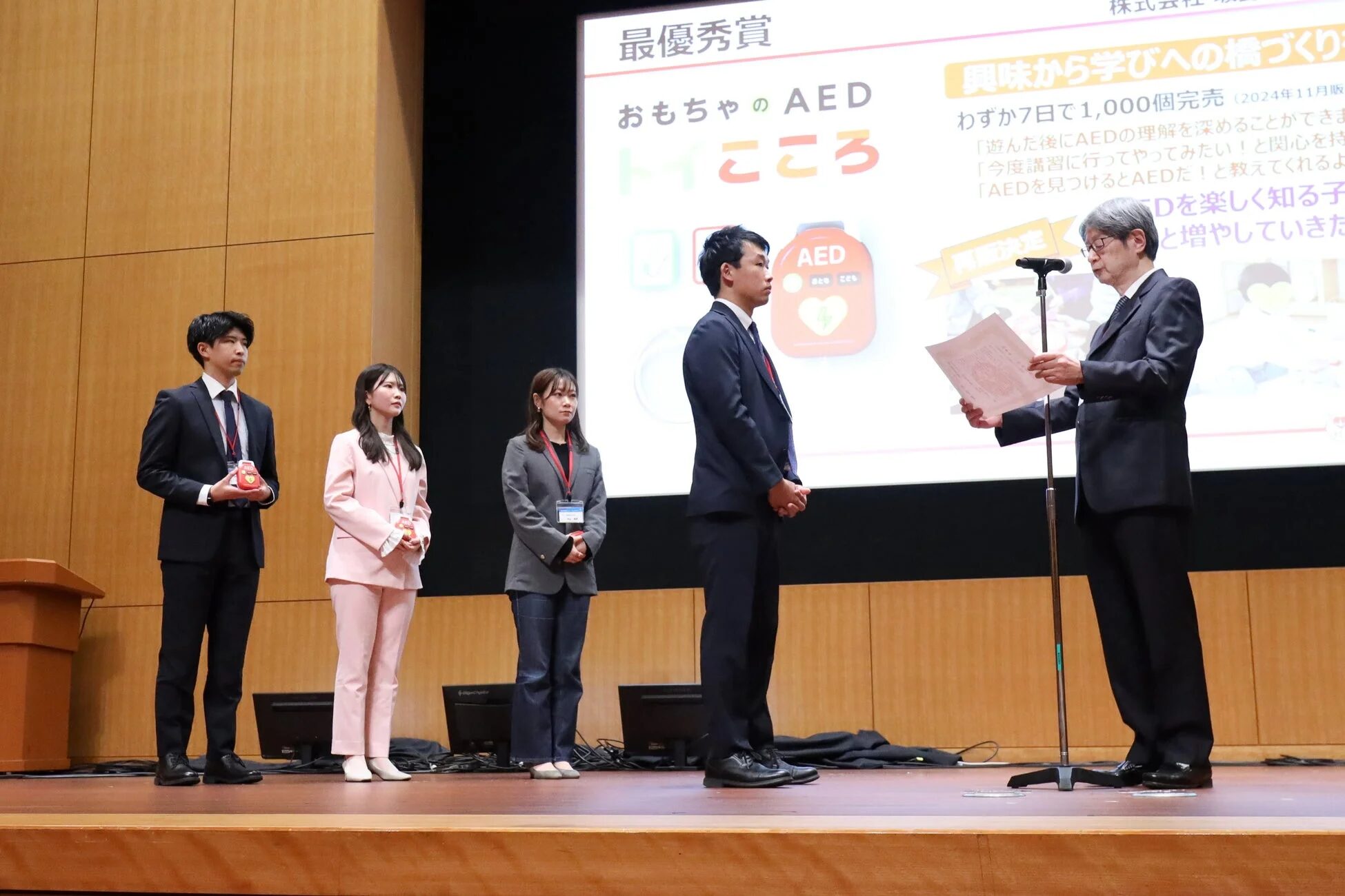 AED功労賞・最優秀賞を受賞し登壇する3名