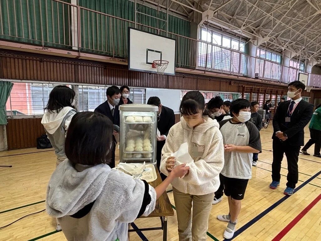 子どもたちが蒸し器から温かい食べ物を受け取っている様子