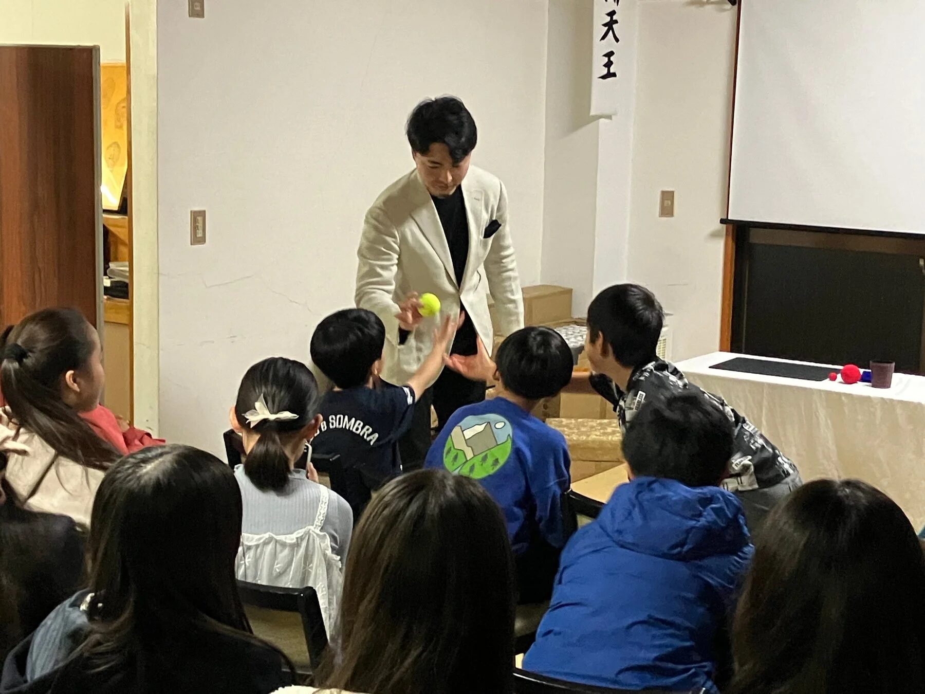 男性が子供たちを前に黄色いボールを使ったパフォーマンスを披露