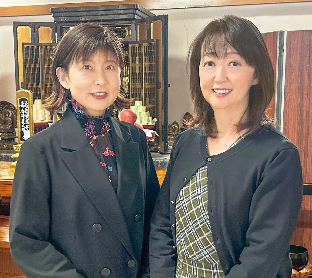 笑顔の女性二人が仏壇の前で並んで立っている写真