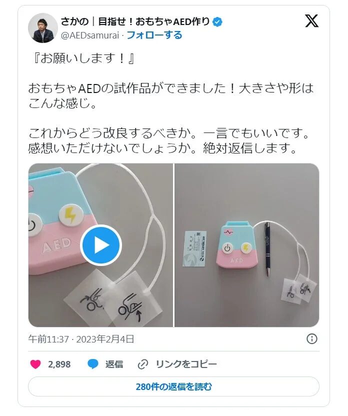 おもちゃのAED試作品が完成し、投稿者が改良点の意見を募っているソーシャルメディアの投稿です。試作品の全体像と詳細がわかる写真が2枚掲載されています。