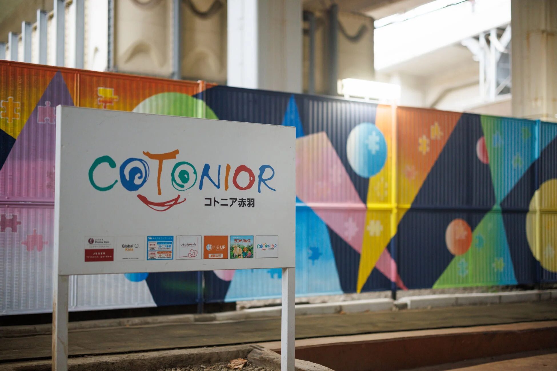 「COTONIOR コトニア赤羽」と書かれた看板が中央に立つ、色鮮やかな壁画が特徴的な商業施設の風景