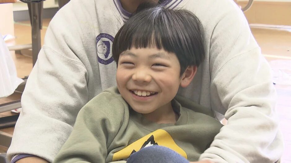 大人の腕に抱かれて満面の笑みを浮かべる男の子