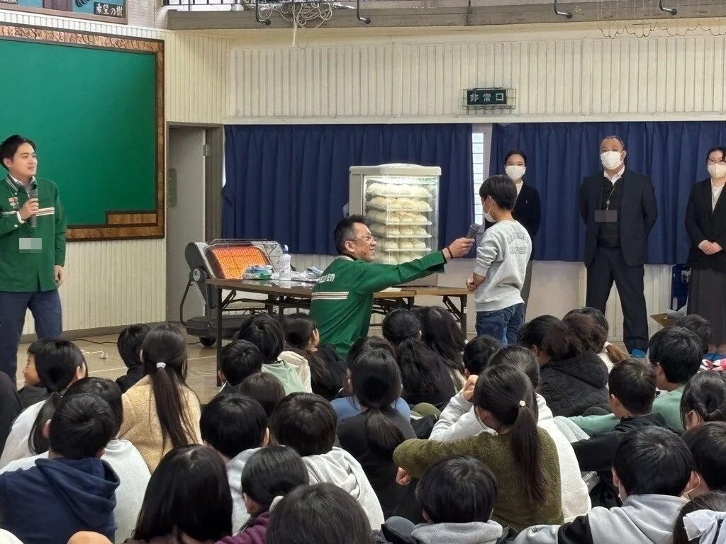 緑色の制服を着た大人が子どもたちにプレゼンテーションをしている様子