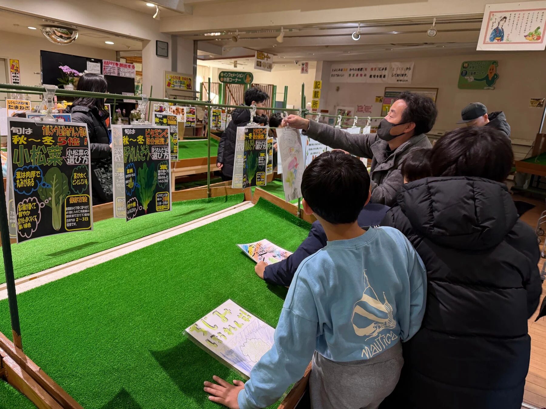 親子連れが野菜の選び方や栄養に関する情報ディスプレイを見ている