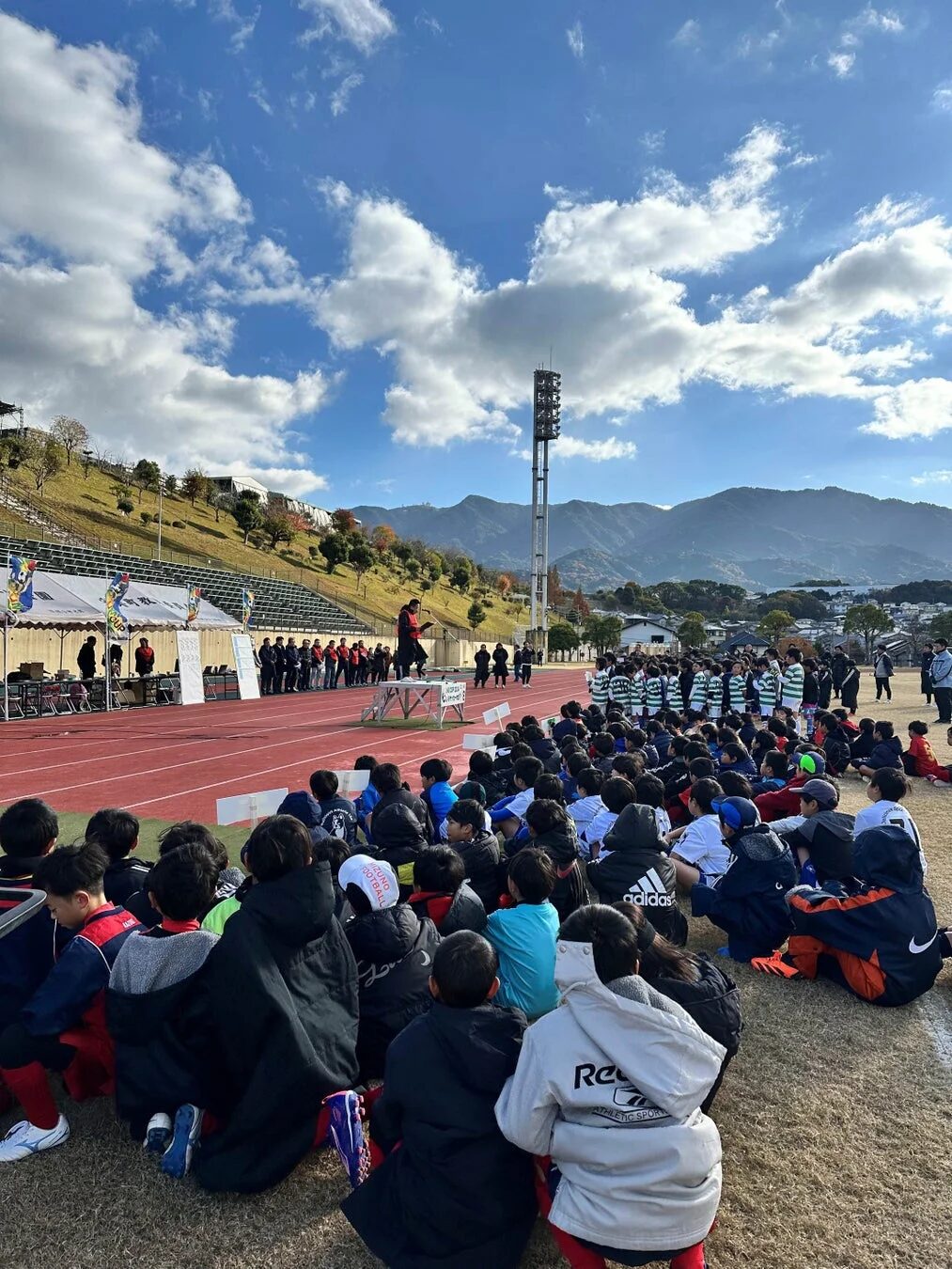 サッカーイベントで指導者の話を聞く子供たち