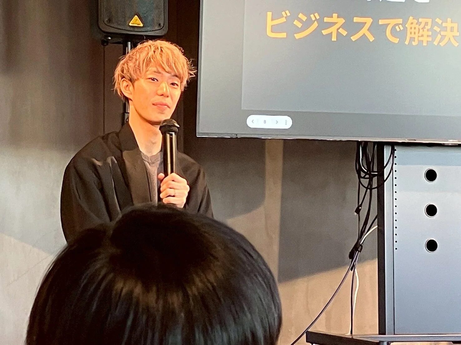男性がプレゼンテーション、スクリーンに「ビジネスで解決」