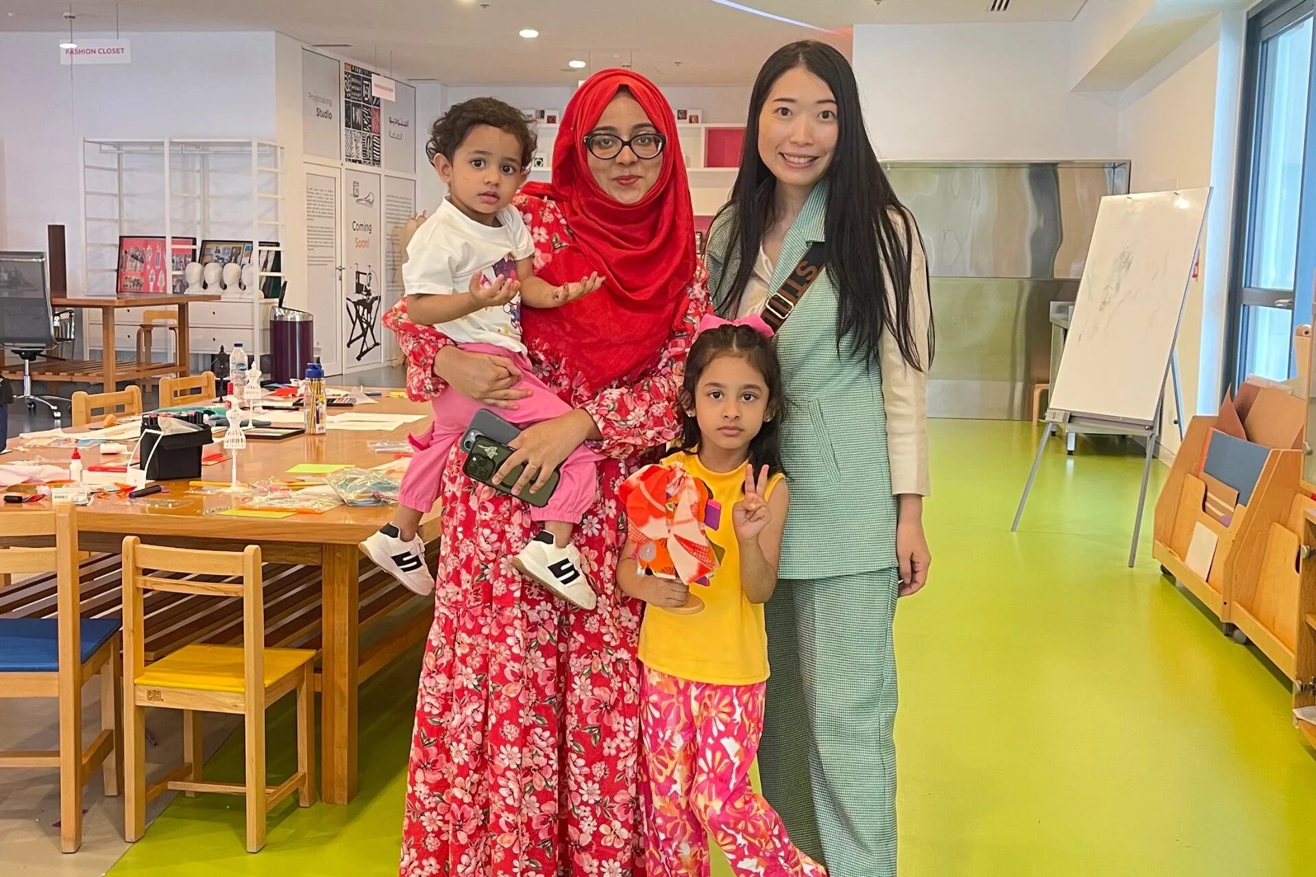 クリエイティブなスタジオのような空間で、3人の女性と2人の子供が一緒に立っている写真です。