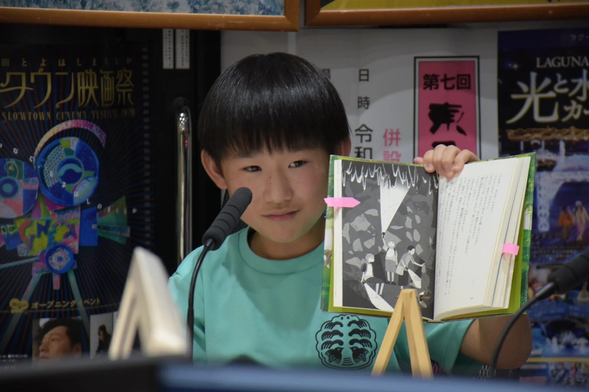 マイクの前で本を朗読する少年