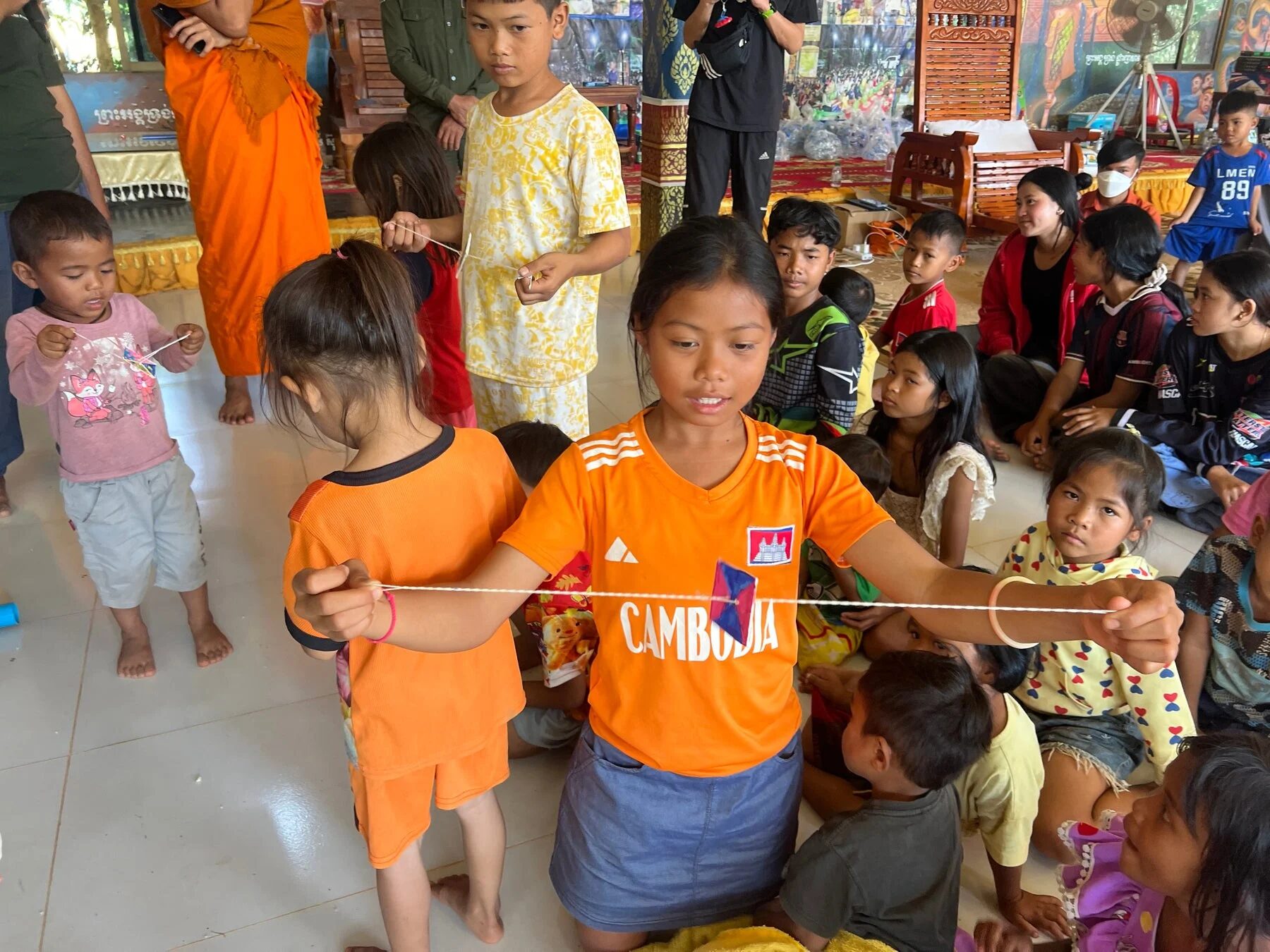 屋内で紐を使った活動をする子どもたちと大人