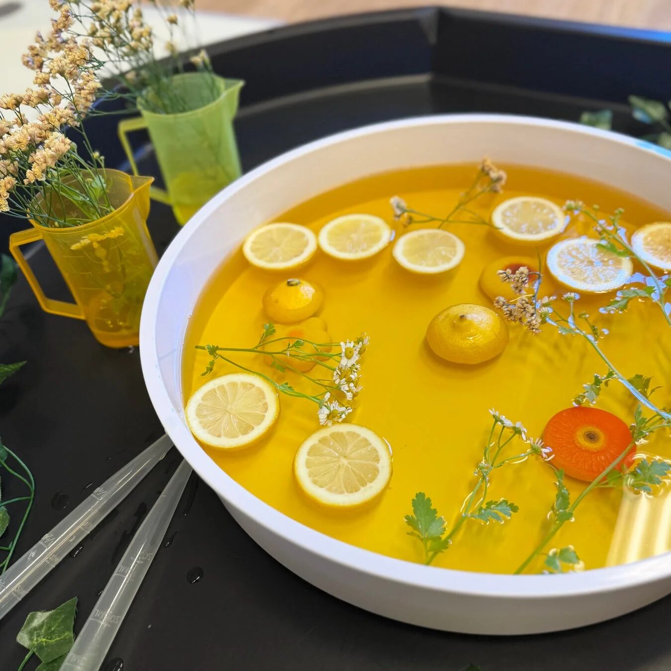 レモンのスライスや花が浮かんだ黄色い水が入ったボウルでのセンサリープレイ