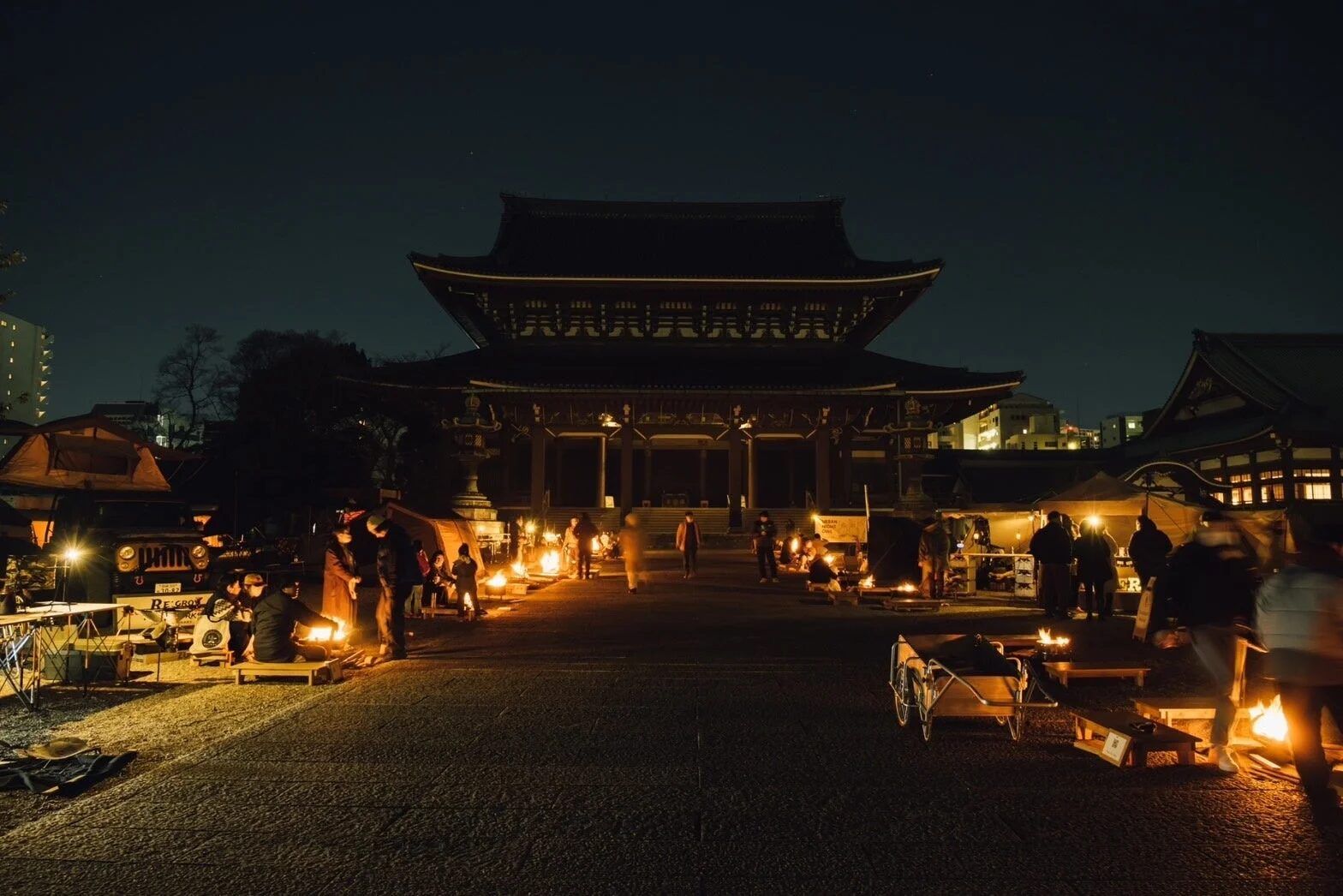 夜の寺院で焚き火を囲む人々